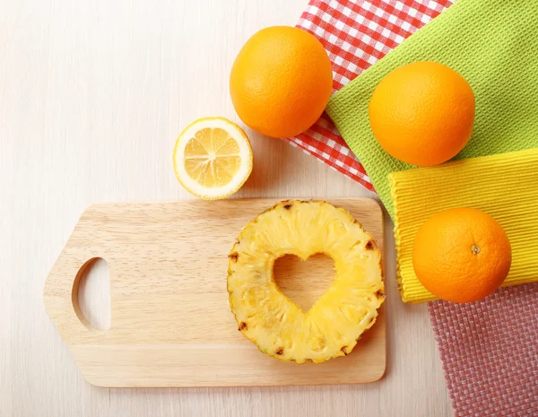 Rebanada de piña con corte en forma de corazón y diferentes frutas en la mesa de cerca — Foto de Stock