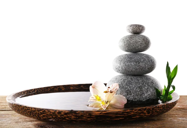 Spa stones with alstroemeria and bamboo in wooden tray with water isolated on white — Stock Photo, Image