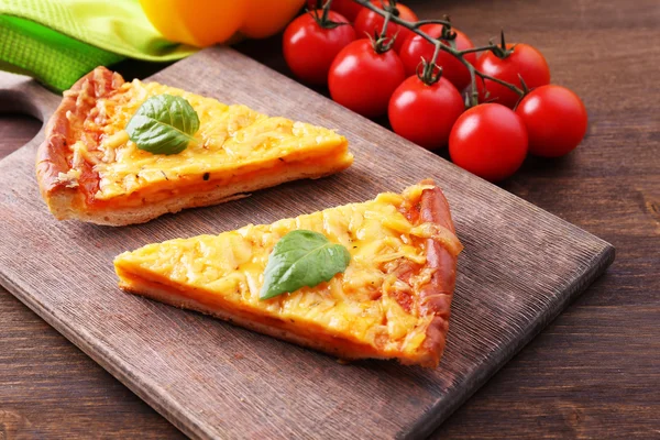 Slices of tasty cheese pizza with basil and vegetables on table close up — Stock Photo, Image