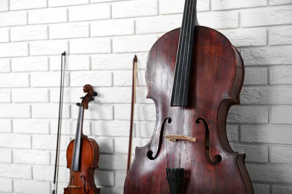 Cello en viool op bakstenen muur achtergrond — Stockfoto