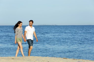 Genç bir çift sahilde yürüyor.