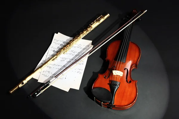 Violín y flauta con notas musicales sobre fondo oscuro —  Fotos de Stock