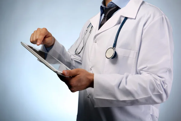 Tablet üzerinde mavi arka plan ile erkek doktor — Stok fotoğraf