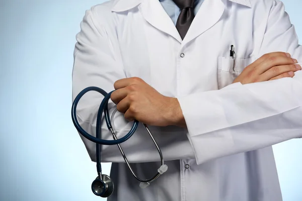 Médico masculino segurando estetoscópio em fundo azul — Fotografia de Stock