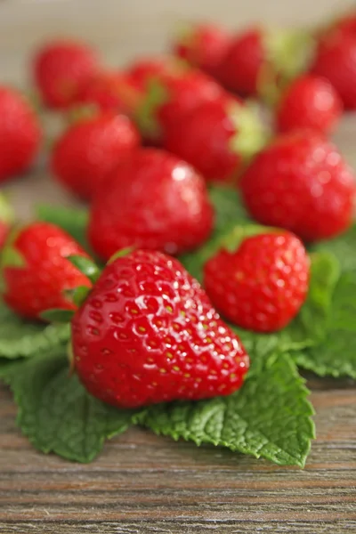 Reife Erdbeeren mit Blättern auf Holztisch, Nahaufnahme — Stockfoto