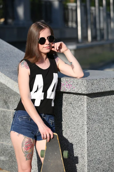 Beautiful tattooed girl with skateboard, outdoors — Stock Photo, Image