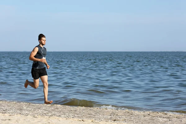 Ung man joggar på stranden — Stockfoto