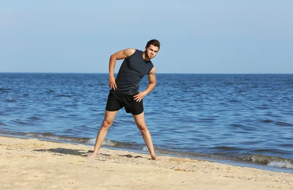 Genç adam sportif plajda egzersiz yaparak