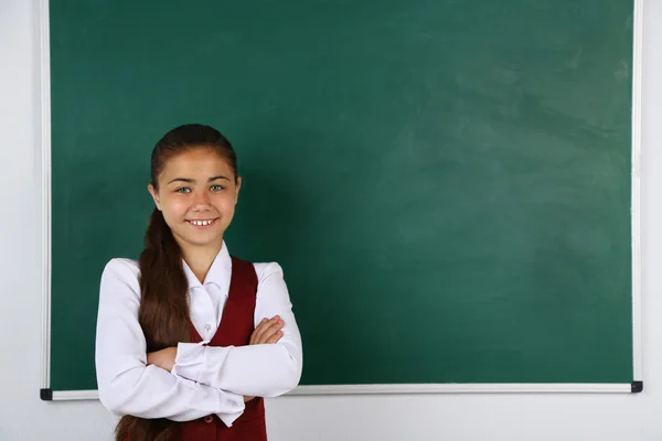 Hermosa niña de pie cerca de pizarra en el aula —  Fotos de Stock