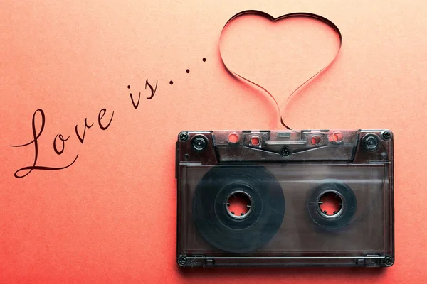 Cassette de audio con cinta magnética en forma de corazón sobre fondo rojo — Foto de Stock