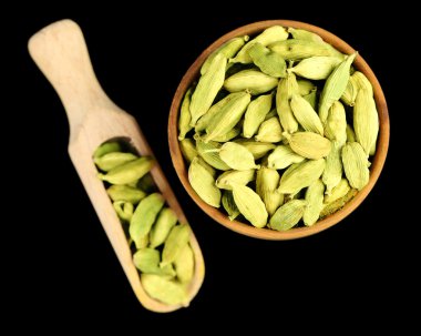 Cardamom in wooden bowl, on black background