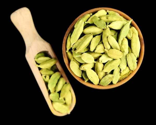 Cardamom in wooden bowl, on black background — 图库照片