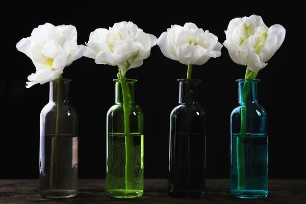 Tulipes fraîches dans des vases en verre sur fond noir — Photo