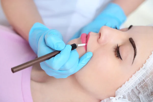 Cosmetólogo aplicando maquillaje permanente en los labios —  Fotos de Stock