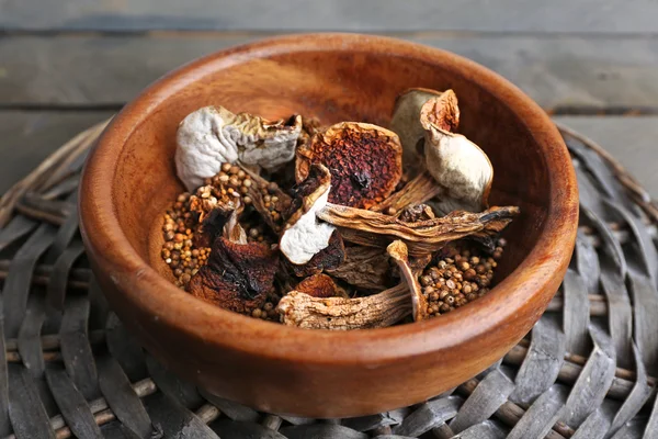 Dried mushrooms in bowl on wicker mat, closeup — Zdjęcie stockowe