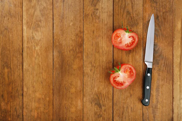 Moitiés de tomate avec couteau sur fond en bois — Photo