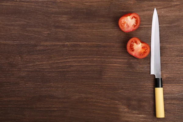 Půlky rajčat s nožem na dřevěné pozadí — Stock fotografie