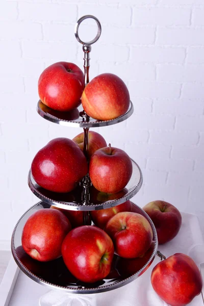 Sabrosas manzanas maduras en bandeja de servir sobre fondo de pared de ladrillo —  Fotos de Stock