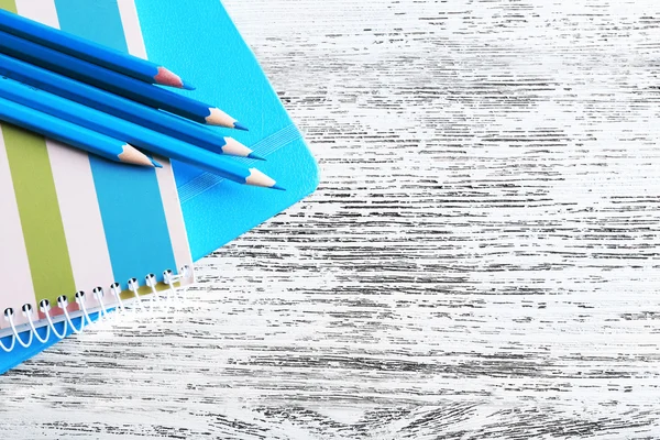 Turquoise crayons and diary on wooden table, closeup — Stock Photo, Image