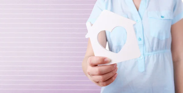 Mano femminile con piccolo modello di casa isolata su bianco — Foto Stock