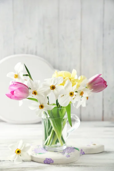 Voorjaar boeket in glazen mok op een houten achtergrond kleur — Stockfoto