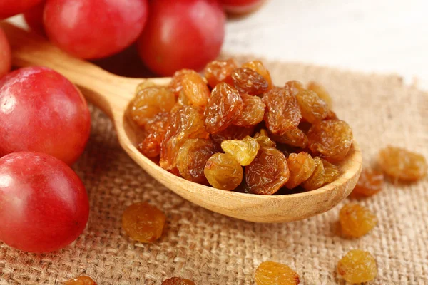 Raisins in wooden spoon with grapes on table close up — Stock Photo, Image