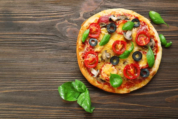 Tasty pizza with vegetables and basil on wooden background — Stock Photo, Image