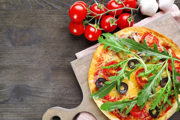Smakelijke pizza met groenten en rucola op snijplank op tafel close-up — Stockfoto