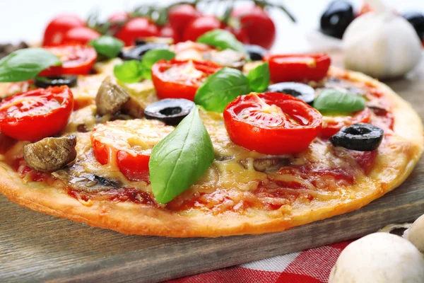 Gustosa pizza con verdure e basilico in tavola da vicino — Foto Stock