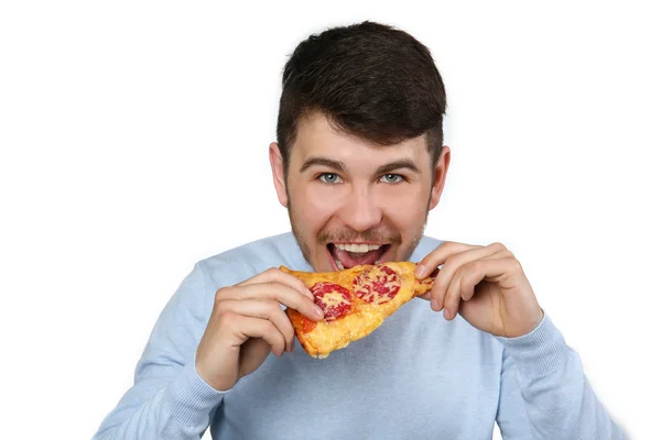 Молодой человек ест пиццу на сером фоне — стоковое фото