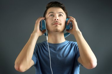 yakışıklı genç adam gri arka planda müzik dinlemek