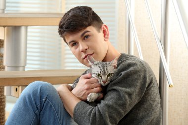 yakışıklı delikanlı ile evde basamaklarında oturan sevimli kedi