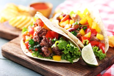 ahşap arka plan üzerinde kesme tahtası üzerinde ev yapımı sığır eti burrito sebzeli patates cips