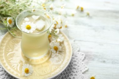 soğuk papatya çayı buz küpleri ve renk ahşap arka plan üzerinde papatya çiçeği ile bardak