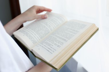 Pencerenin yanında kitap okuyan kadın