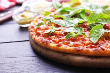 ahşap arka plan üzerinde kesme tahtası üzerinde Fesleğenli pizza