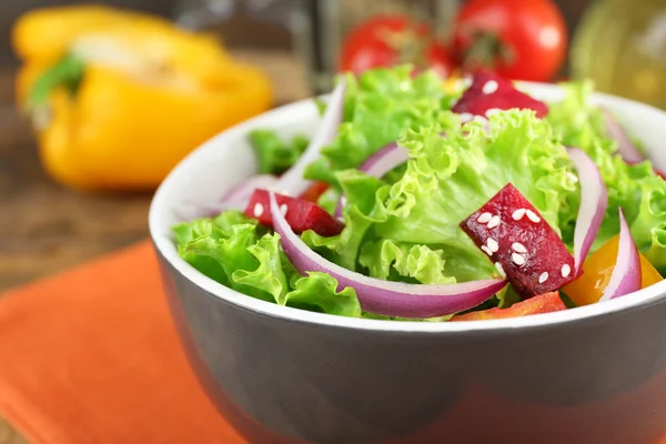 Bowl of fresh green salad on table with napkin, closeup — Stock Photo, Image