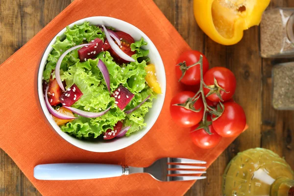 Bowl of fresh green salad on table with napkin, closeup — Stock Photo, Image