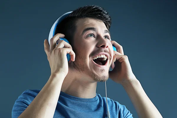 Handsome young man listening to music on  dark background — Stock Photo, Image