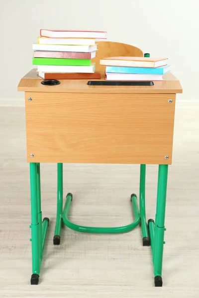 Wooden desk with books and chair in class on blackboard background — Stock Photo, Image