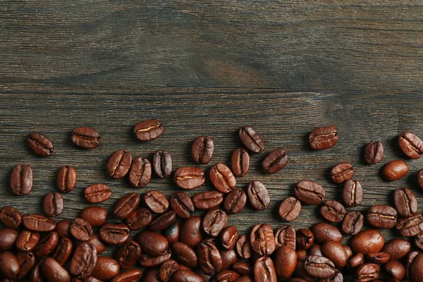 Grãos de café em fundo de madeira — Fotografia de Stock