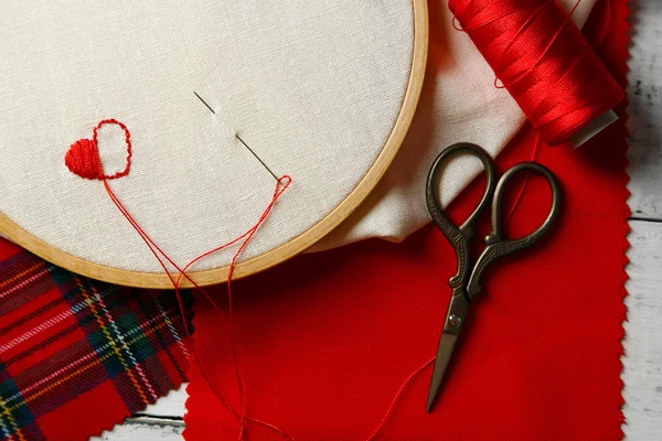 El aro de bordado con tela e hilos de coser rojos en la mesa de cerca —  Fotos de Stock