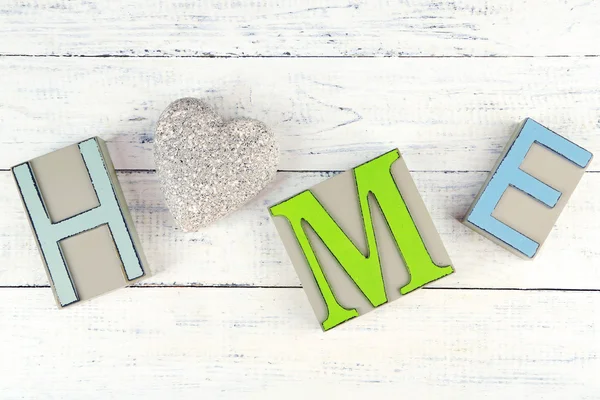 Lettres décoratives formant mot HOME avec coeur décoratif sur fond en bois — Photo