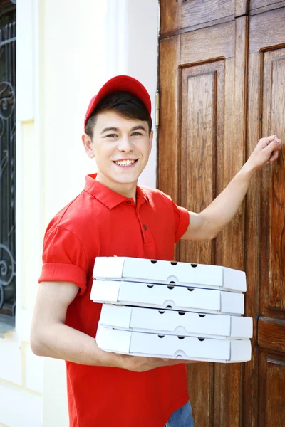 Jeune homme livrant une boîte à pizza près de la maison — Photo