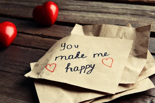 Message écrit avec des cœurs décoratifs sur une table en bois close up — Photo