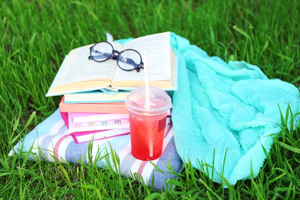Böcker, glasögon och drink på gräs närbild — Stockfoto
