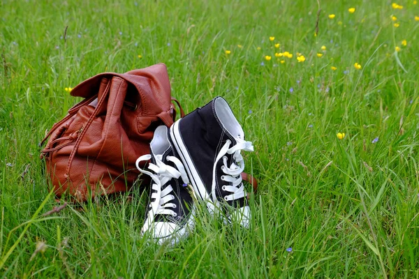 Sneakers and backpack on green grass background — Stock Photo, Image