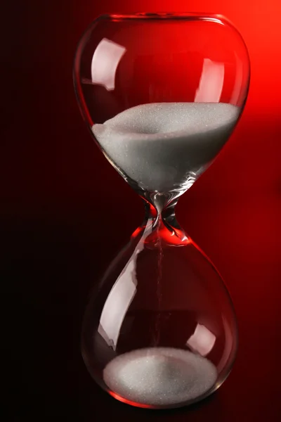 Hourglass on dark red background — Stock Photo, Image