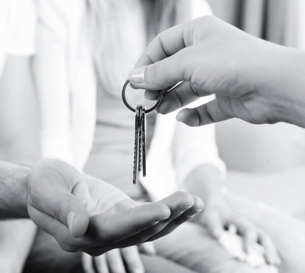Real estate agent giving keys to young couple, closeup