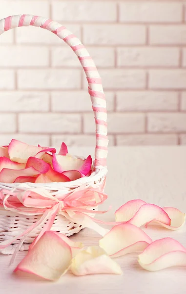 Cesta de boda con pétalos de rosas en la mesa, sobre fondo claro —  Fotos de Stock